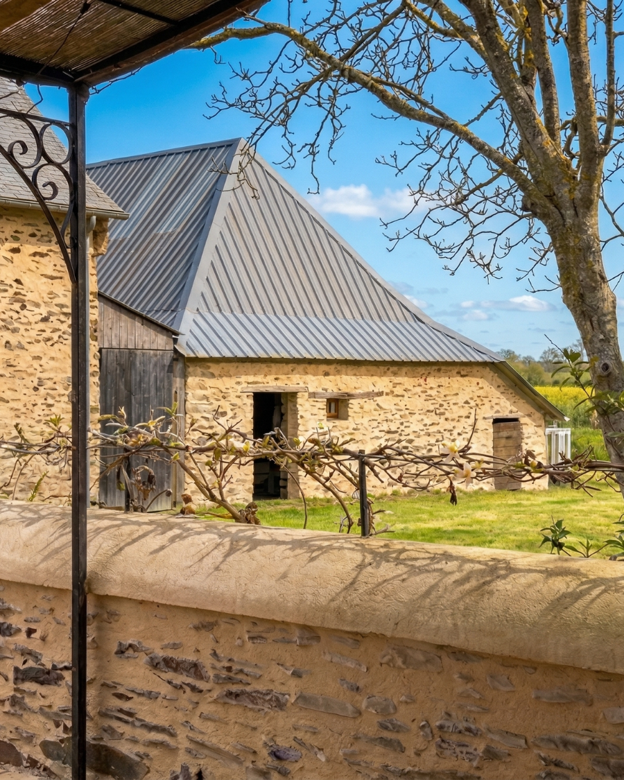 Ferme en pierre avec toiture en zinc, entourée de verdure